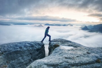 Hiker leaping across gorge