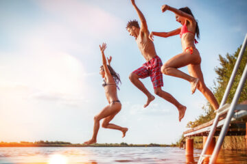 Group of friends jumping into lake
